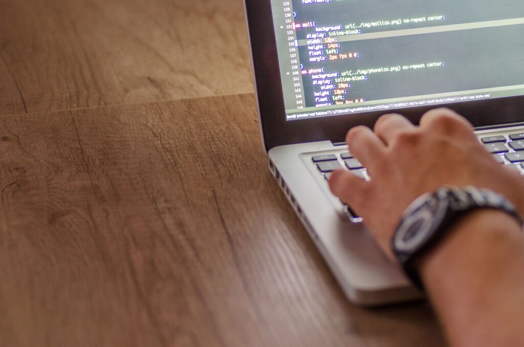 Primer plano de una persona programando en un portátil, mostrando conceptos de desarrollo web y programación.